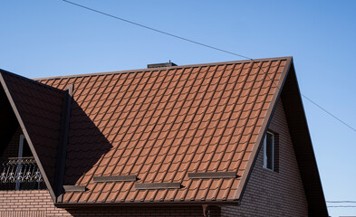 Brown corrugated metal profile roof installed on a modern house. The roof of corrugated sheet. Roofing of metal profile wavy shape. Modern roof made of metal. Metal roofing.