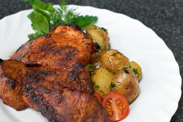 Roasted pork with baked potatoes, herbs and tomatos.