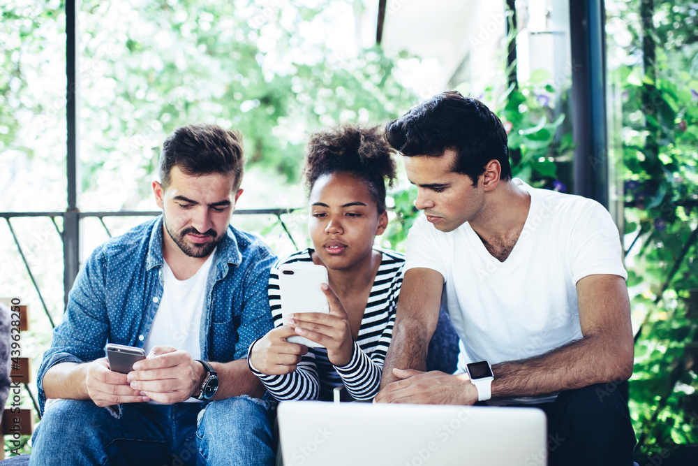 Poster multiracial male and female colleagues creating web publication in social media using smartphone tec