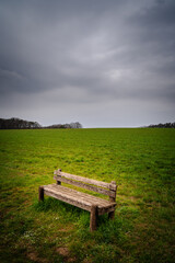Dark and rainy clouds over bench in the countryside
