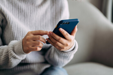 close up view of young women using a smartphone on sofa in living room, lifestyle modern female.