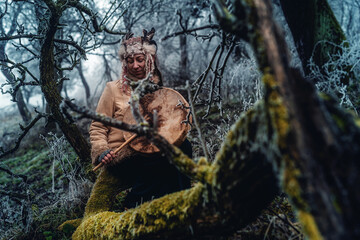 Obraz premium beautiful shamanic girl playing on shaman frame drum in the nature.