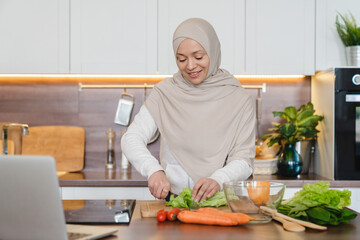 Healthy eating habits, mature muslim islamic wife woman in hijab cooking preparing vegetable salad...