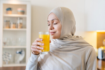 Fit mature arabian muslim islamiic woman in hijab drinking orange juice fresh smoozie in the...