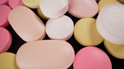 Multi-colored pills lie on the table. The tablets are scattered onto the rotating medical table. Analysis laboratory. The invention of pills for coronavirus. Tablets on a turntable.