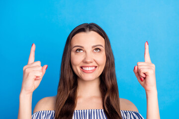 Photo portrait woman pointing finger up copyspace smiling advising happy isolated vivid blue color...
