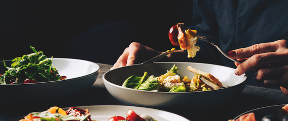 woman eating healthy salad from bowl sitting in cafe