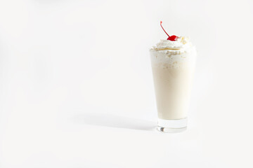 Milkshake in a glass with whipped cream and cherries.