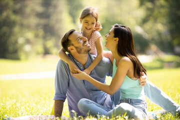 Happy young family with cute little daughter having fun in the park on a sunny day