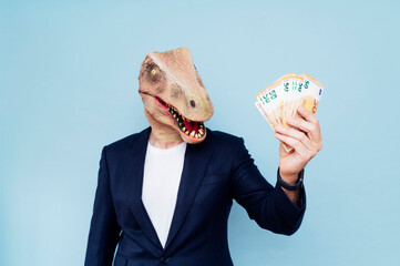 Attractive man with dinosaur mask holding his money.