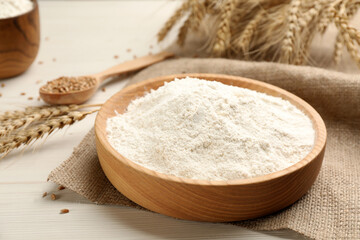 Plate with wheat flour on white wooden table