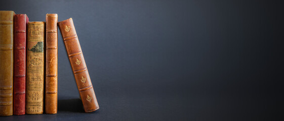 Row of old books on dark background banner