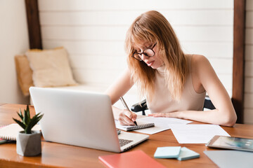 E-learning, webinars, college homework concept. Businesswoman tutor freelancer making notes using...