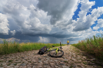 Fototapeta na wymiar traveling on a bicycle, a man looks at a thunderstorm