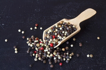 Colorful pepper corns in wooden spoon on wooden background