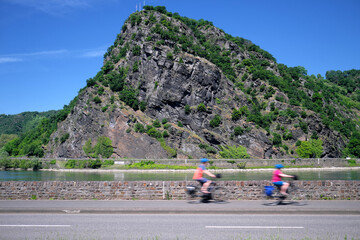 Radfahrer auf Radweg am Rhein entlang an der Loreley bei sonnigem Wetter - Stockfoto