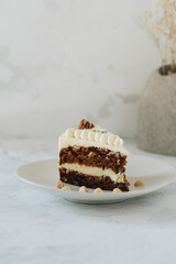 Piece of carrot homemade cake with white cream on a white background.