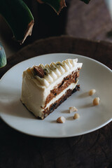Piece of carrot homemade cake with white cream on a white plate