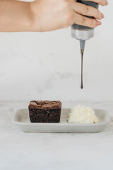 Woman pouring brownie with chocolate sauce