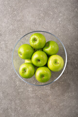 Ripe green apples in a bowl on a gray background