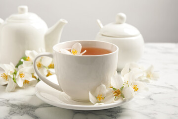 Fototapeta na wymiar Aromatic jasmine tea and fresh flowers on white marble table