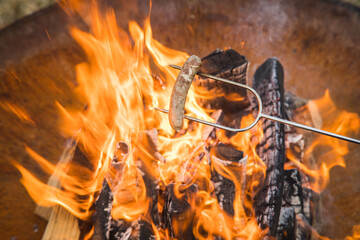 Nürnberger Bratwurst grillen am Spieß über Lagerfeuer Holz Feuer einer Metall Feuerschale im Garten