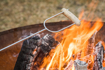Nürnberger Bratwurst grillen am Spieß über Lagerfeuer Holz Feuer einer Metall Feuerschale im...
