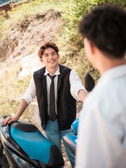 A young asian man listens avidly to some compliments about his motorbike.