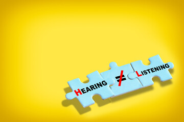 Hearing is not same as listening written on blue puzzle isolated on yellow background. Business leadership concept and teamwork to communication idea