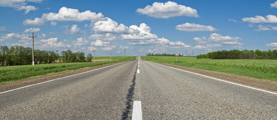 the road leading into the distance clouds and fields