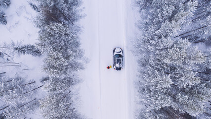 Aerial view from drone of car stopping to pick up hitchhikers explore wild destinations on journey, bird’s eye view of two persons get into transport discover north cold lands on road trip in winter