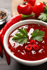 Spicy chili sauce with parsley on table, closeup
