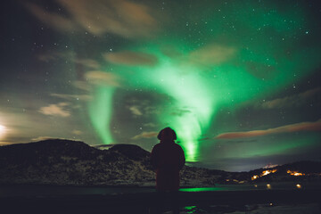 Traveler observing sky with glowing northern lights