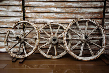 Fototapeta na wymiar wooden wall of a building based on its old wooden wheels and hanging tools on agricultural
