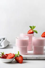 Three Strawberry lassi, smoothie or milkshake on a white background. Vertical format. Healthy ayurvedic Indian beverage. Drink to improve digestion.