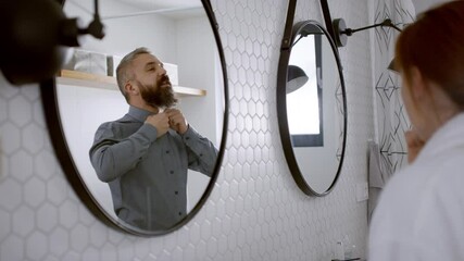 Couple in bathroom getting ready for work in the morning.