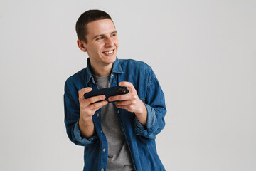 Young brunette man smiling and holding cellphone