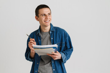 Young brunette student man smiling while holding exercise books
