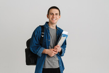 Young brunette student man smiling while holding exercise books - obrazy, fototapety, plakaty