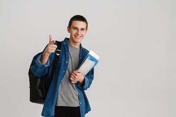 Young student man pointing finger while holding exercise books