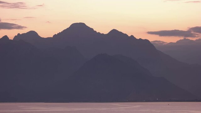 Panoramic night view of sea, mountains and coastal city buildings.