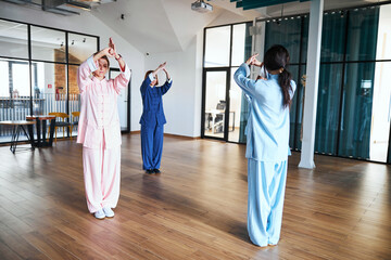 Three women practicing specific body postures of qigong