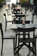 Rows of empty black restaurant terrace tables