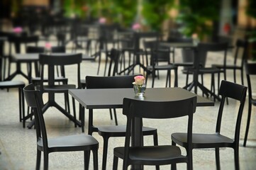 Rows of empty black restaurant terrace tables