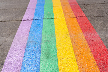 Gay pride flag crosswalk on the road of a city - obrazy, fototapety, plakaty