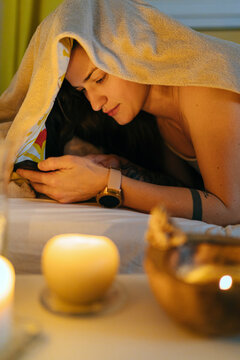 Woman browsing smartphone in cozy bedroom with candles