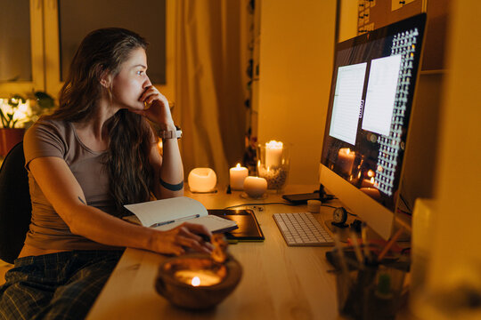 Young woman working on computer in late evening at home