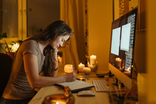 young woman working at the computer and notebook in the late evening