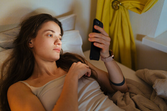 Woman messaging on smartphone in bed