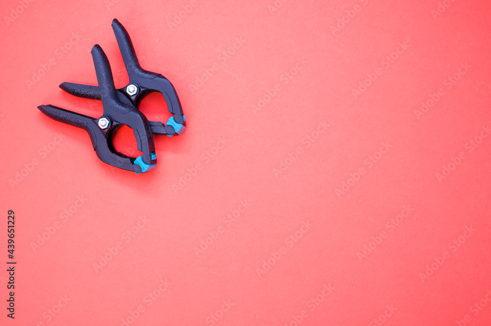 Poster top view of two plastic spring clamp tools isolated on red background